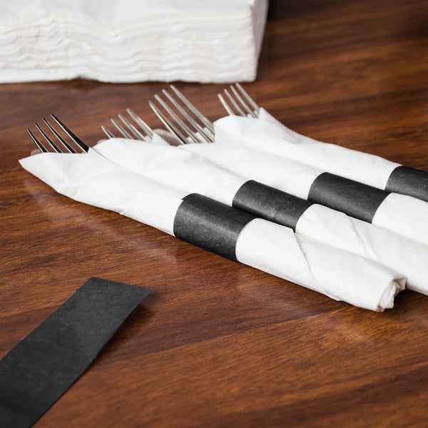 White napkins wrapped around cutlery with black napkin bands